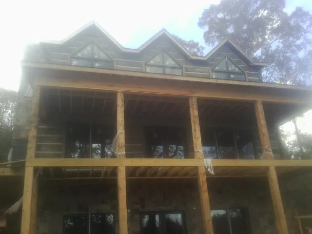 Dormers and porch framing on a large log home under construction — Roof Coating work by our crew in Mc Henry